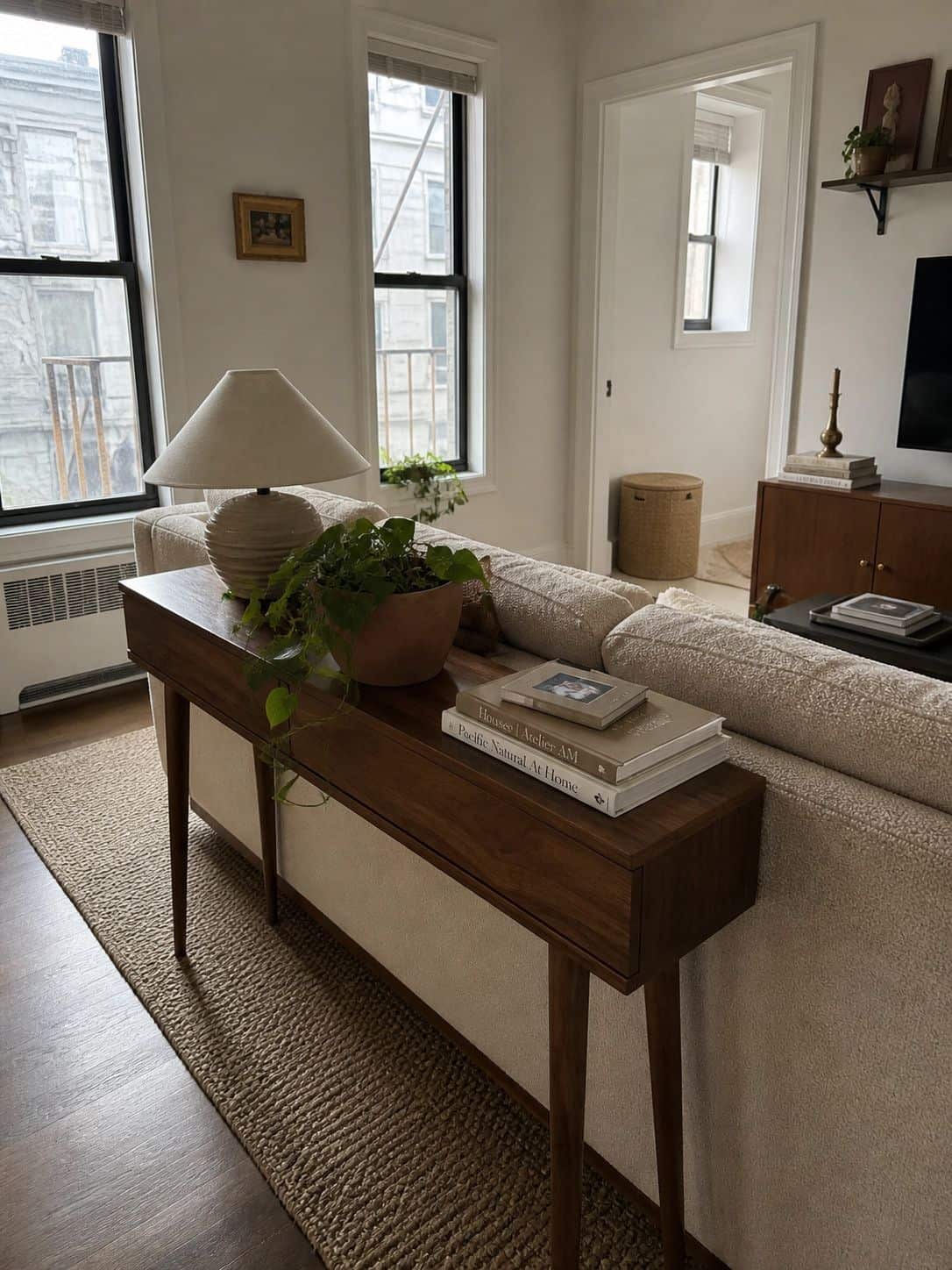 Slim walnut console table behind a sofa in a small apartment living room