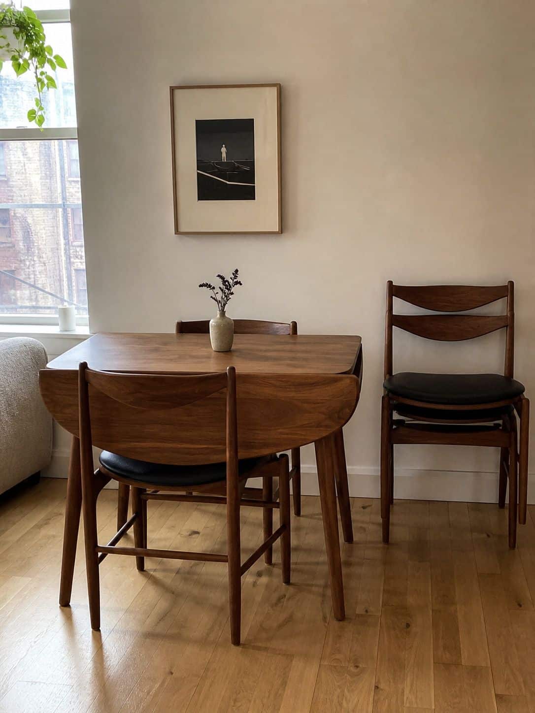 Stackable walnut dining chairs beside a compact table in a small apartment