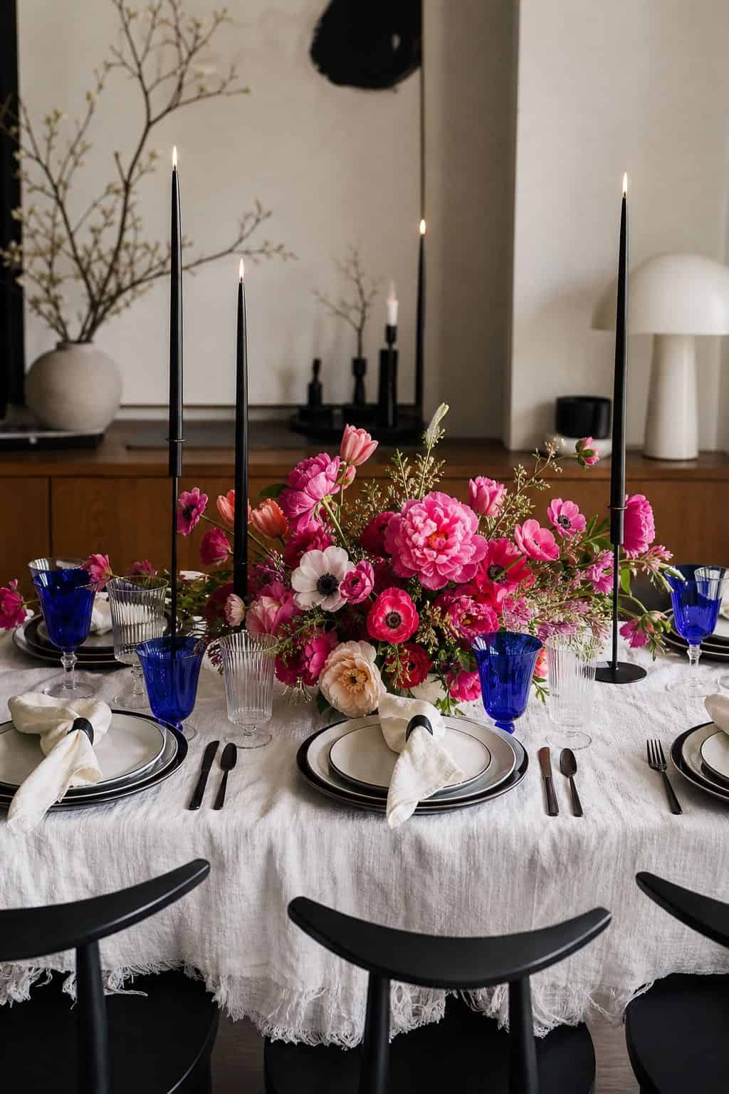 Black and white spring wedding table with hot pink flowers, cobalt glassware, candles, and walnut table