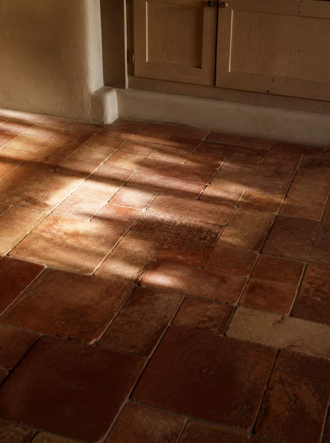 Terracotta tile floor in a Spanish Mediterranean kitchen with sunlight streaming in.
