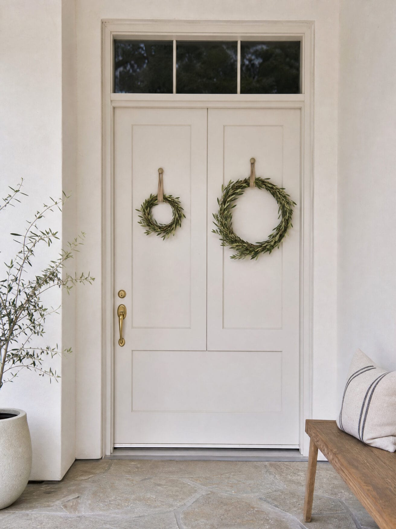 Summer door hanger ideas: two green olive branch wreaths on a light gray front door.