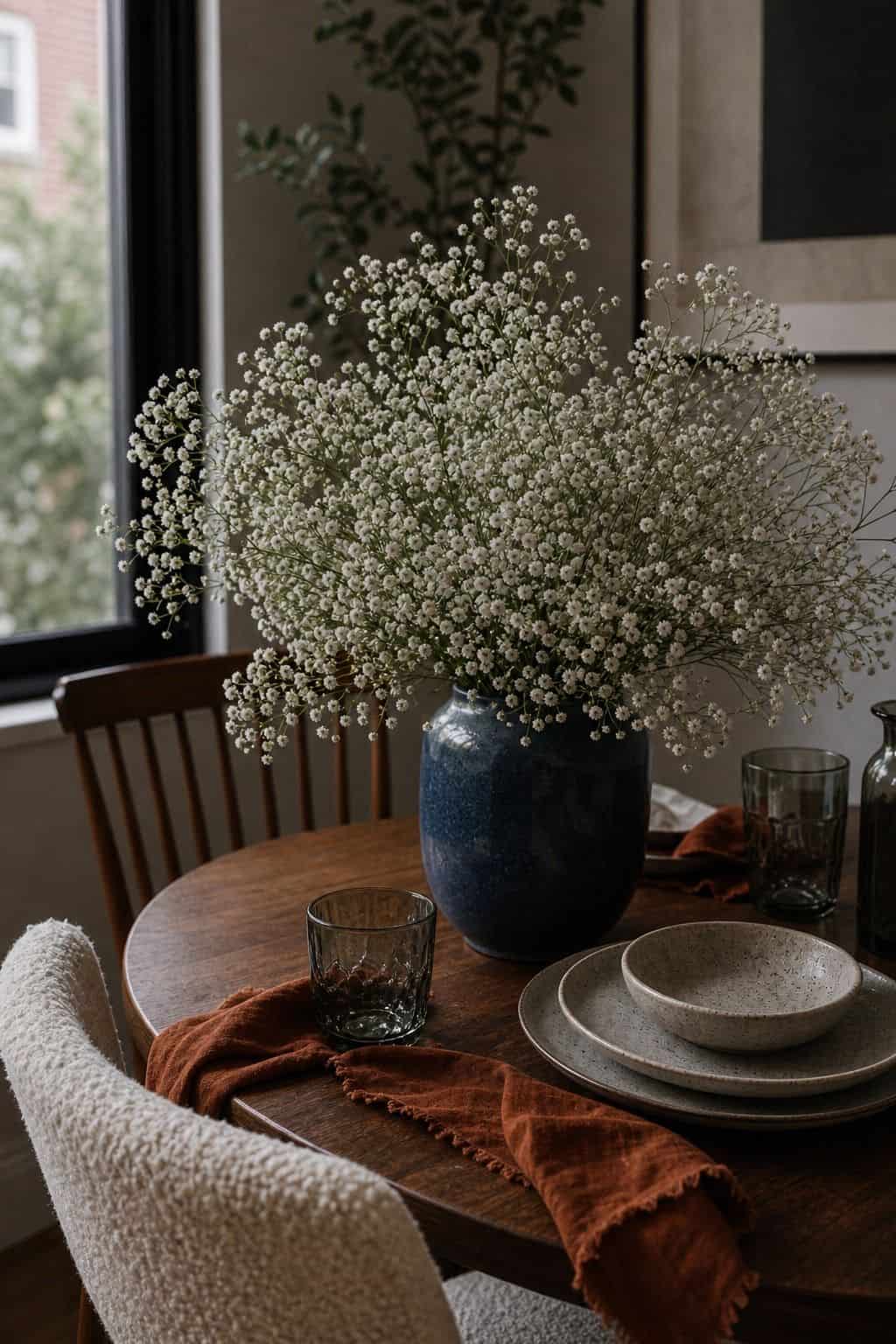 Airy baby's breath in a blue vase on a moody summer wedding table