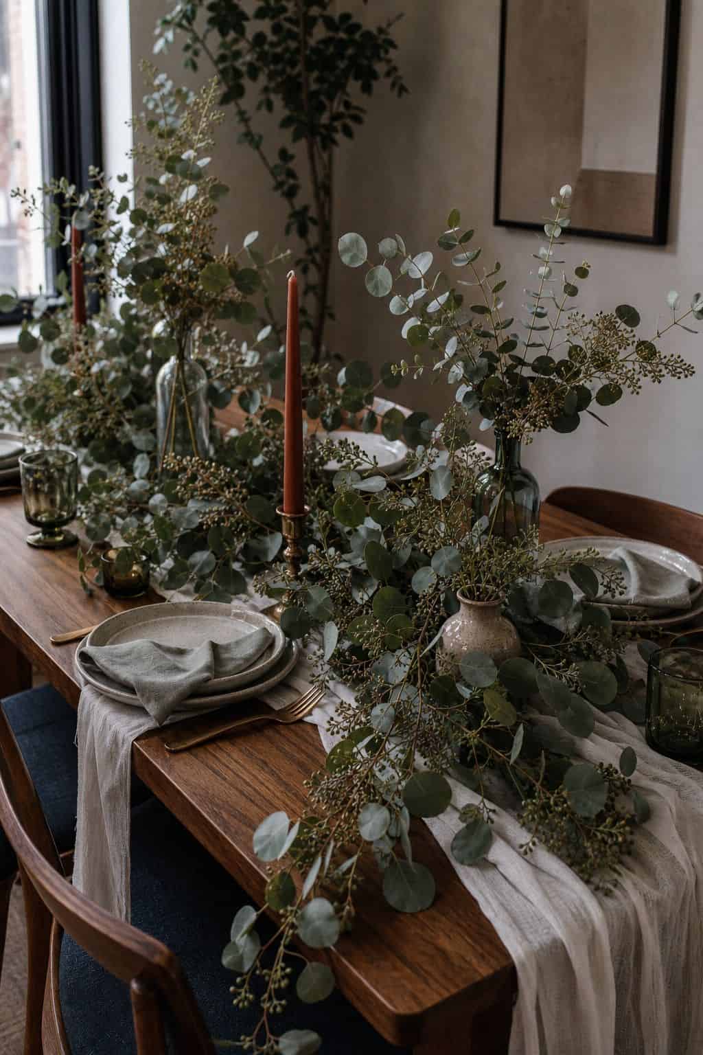 Mixed eucalyptus greenery trailing across a summer wedding table with bud vases