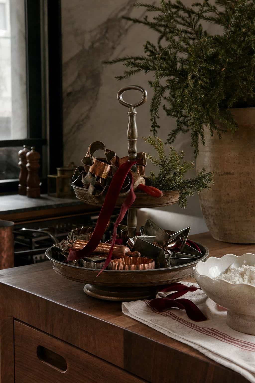 Christmas tiered tray with vintage cookie cutters, tiny baking tools, and red ribbon