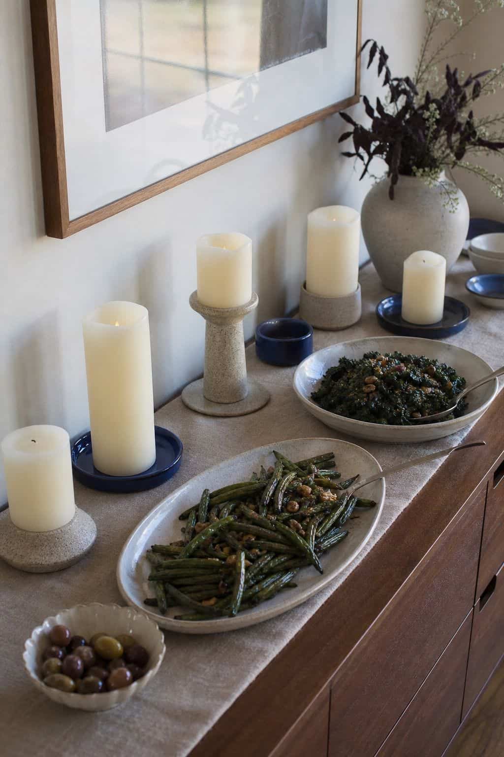 Flameless pillar candles clustered safely behind Thanksgiving buffet dishes with deep blue accents