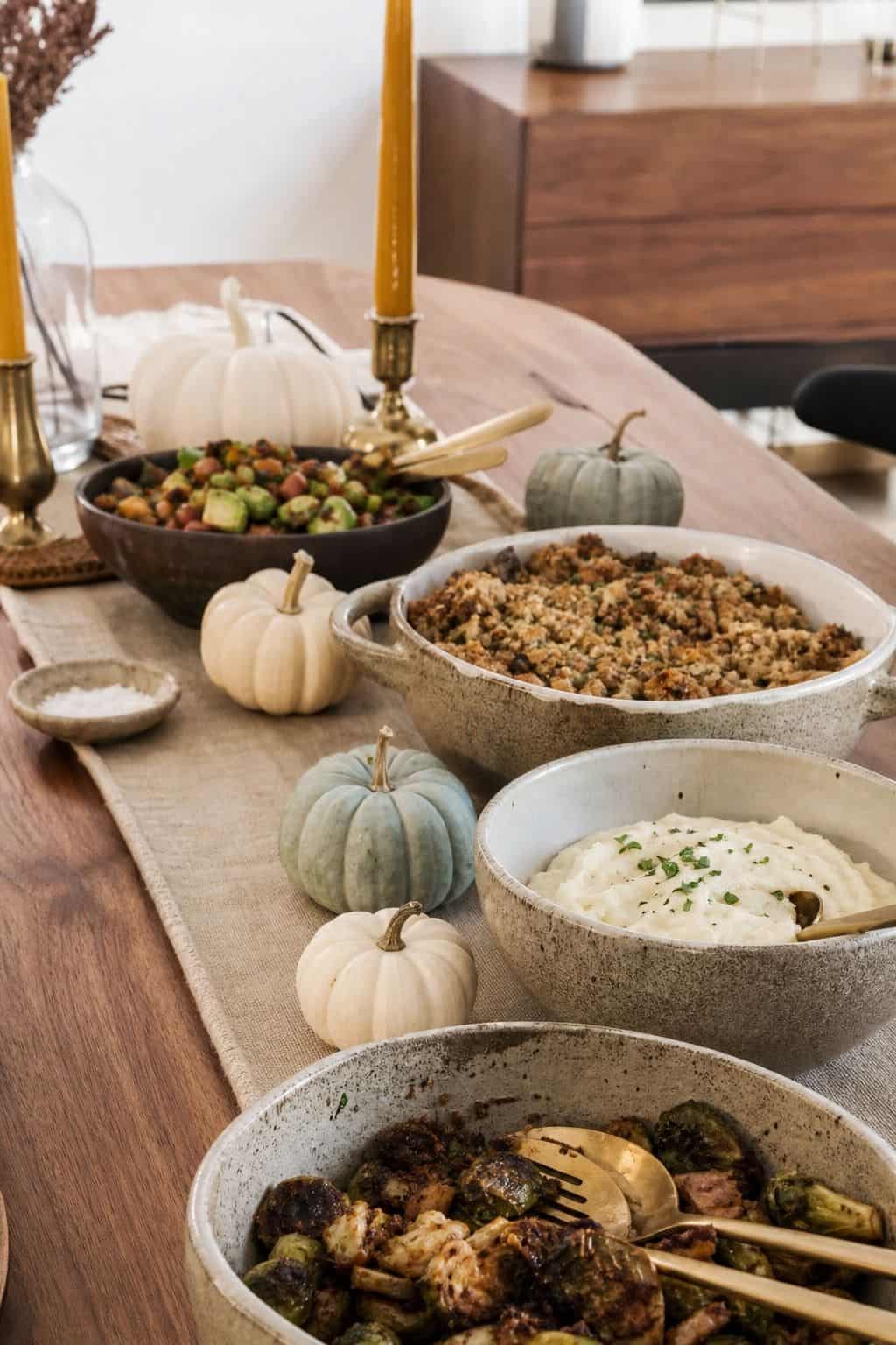 Cream and pale blue mini pumpkins tucked between Thanksgiving buffet serving dishes