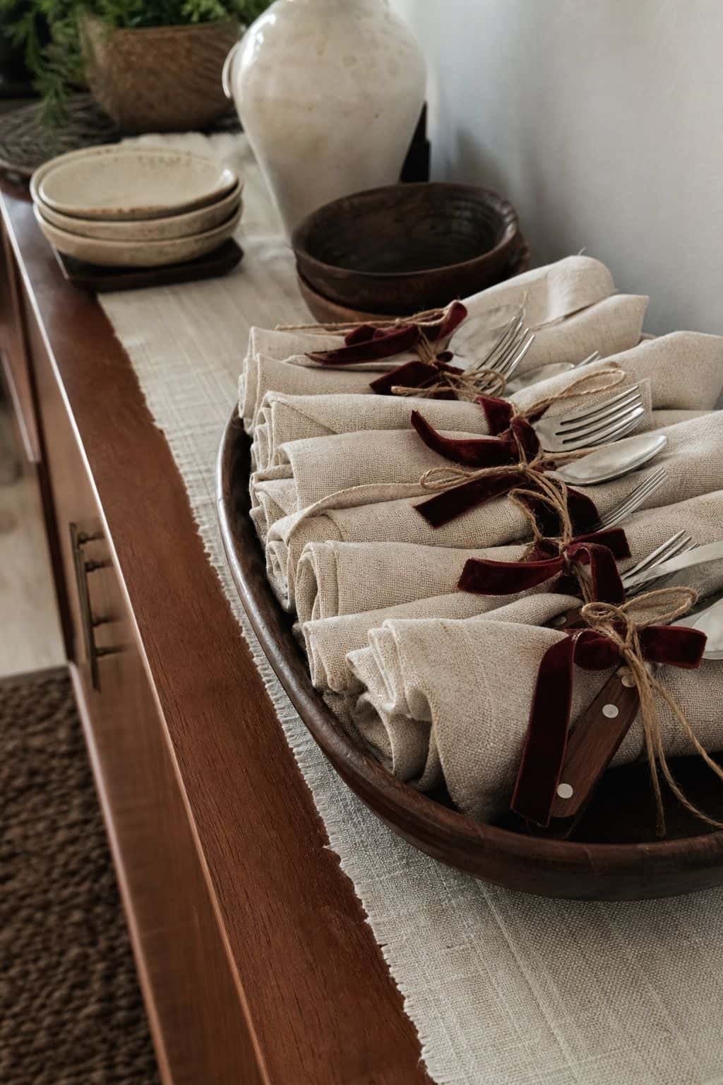 Rolled silverware bundles and folded napkins arranged at the end of a Thanksgiving buffet line