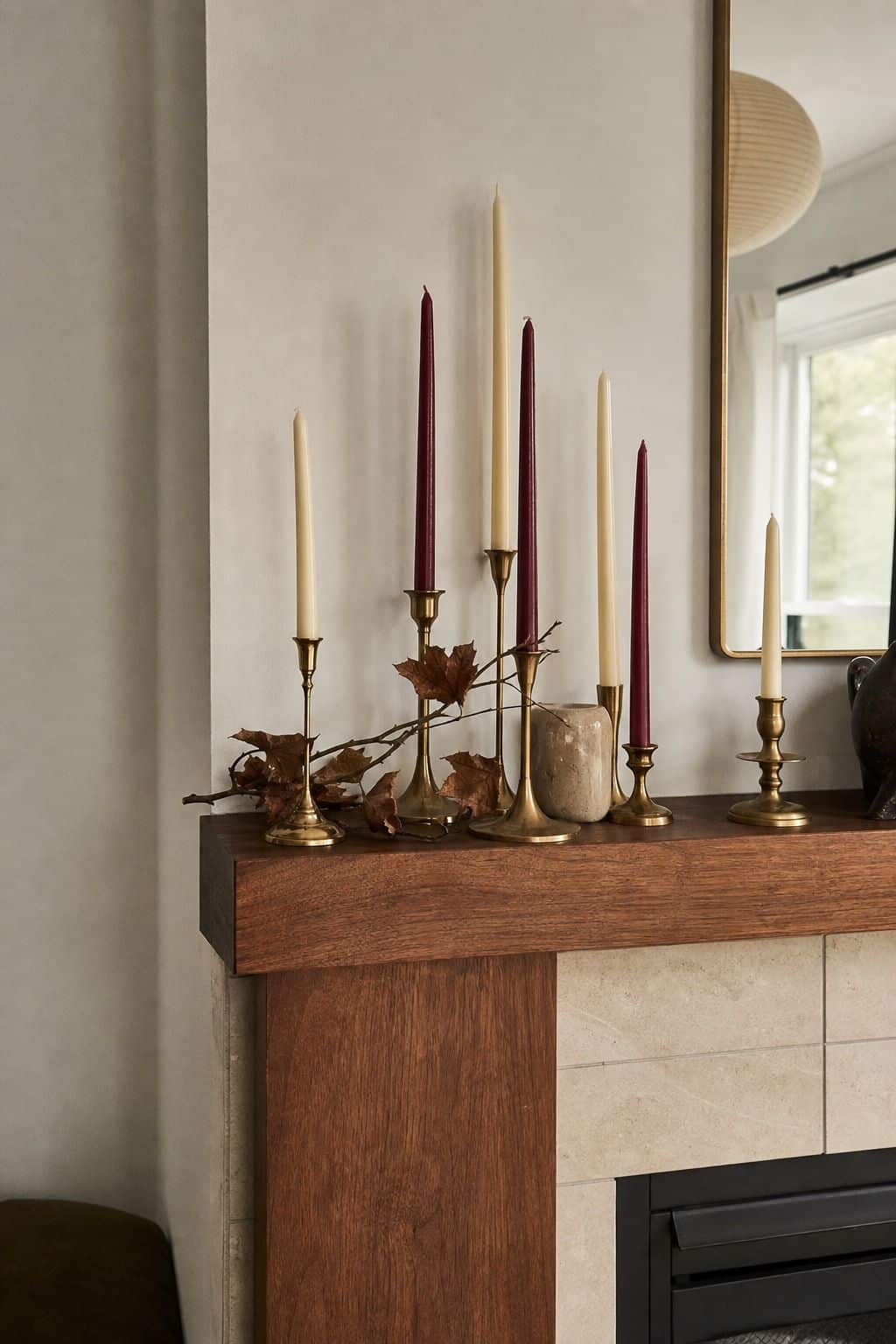 Mixed-height brass candles on a walnut mantel for Thanksgiving mantel decor