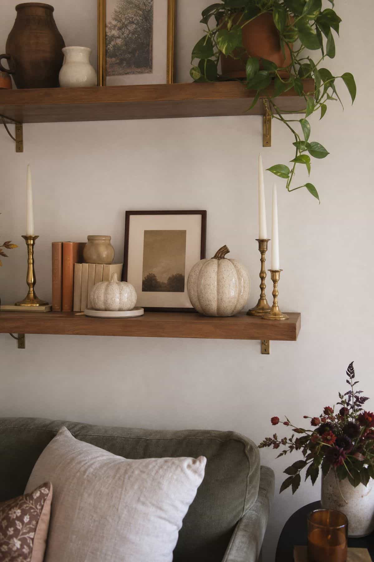 Pair Ceramic Pumpkins with Brass Candlesticks on fall shelves in a small apartment